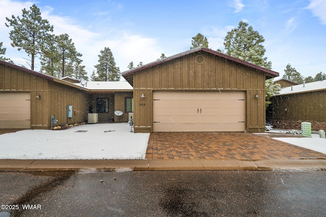 view of front facade with a garage, board and batten siding, and cooling unit
