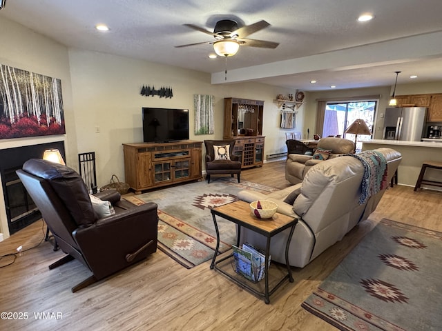 living area featuring light wood-type flooring, a baseboard radiator, a ceiling fan, and recessed lighting