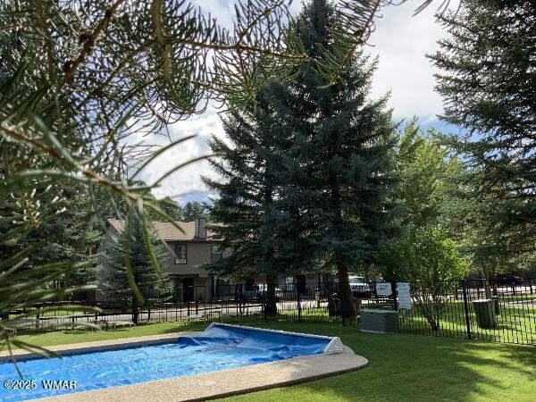 view of swimming pool featuring fence and a lawn