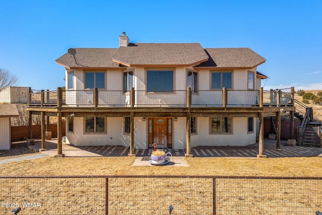 back of house featuring a fire pit, roof with shingles, stucco siding, a chimney, and a patio area