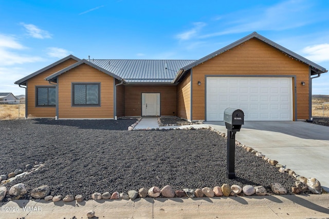 view of front of house with an attached garage, metal roof, and concrete driveway