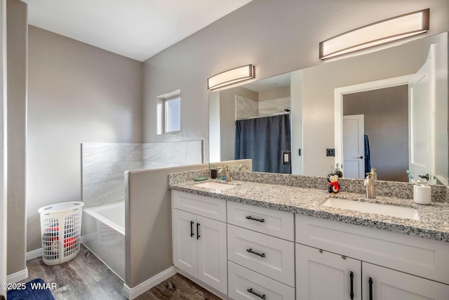 bathroom with double vanity, a washtub, a sink, and wood finished floors