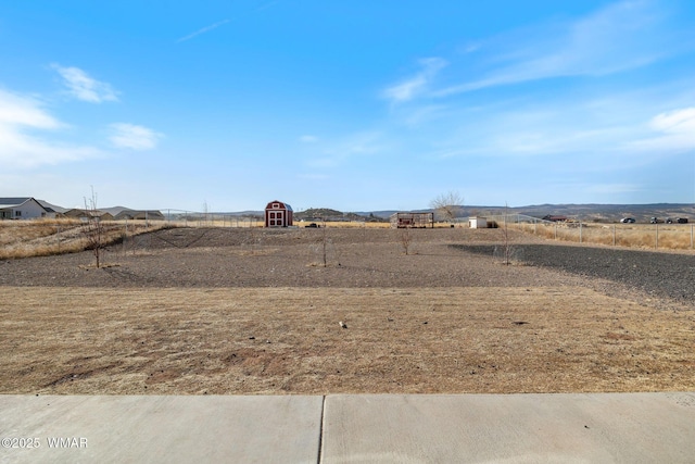 view of yard with a storage unit, a rural view, and fence