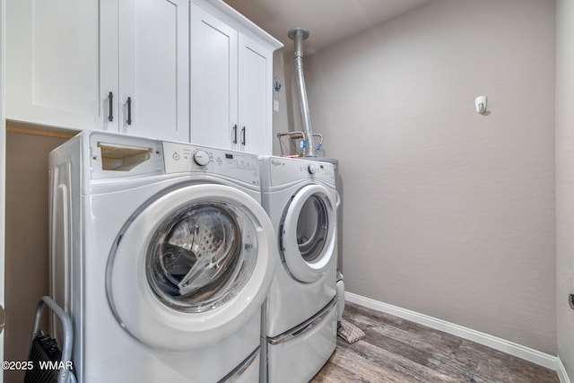 washroom with cabinet space, a textured wall, washing machine and dryer, wood finished floors, and baseboards