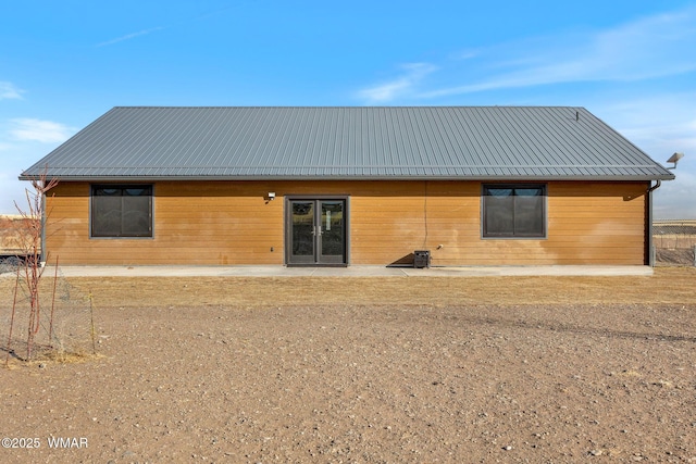 back of property with metal roof and a patio