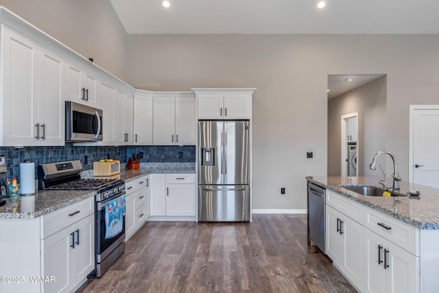 kitchen featuring appliances with stainless steel finishes, white cabinets, a sink, and light stone counters