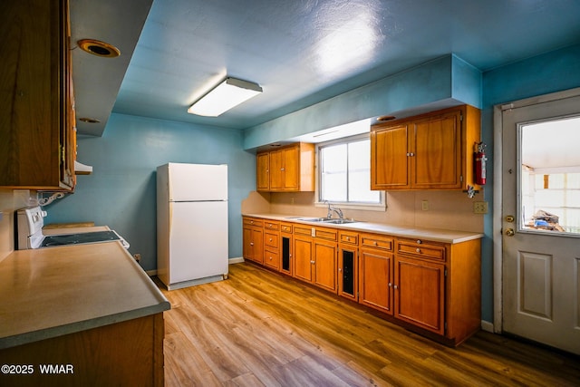260 E 1st St, Snowflake, AZ 85937 - kitchen with white appliances, brown cabinets, light wood-style flooring, and light countertops
