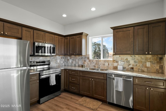 kitchen with wood finished floors, appliances with stainless steel finishes, backsplash, and a sink