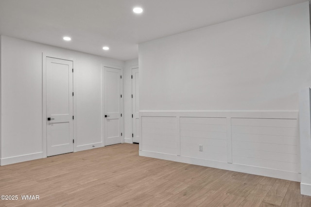 empty room featuring recessed lighting, wainscoting, and light wood finished floors