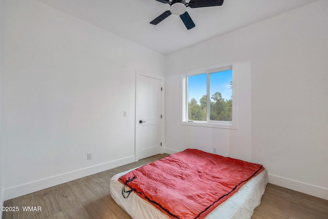 bedroom featuring a ceiling fan, baseboards, and wood finished floors