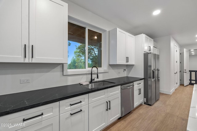 kitchen with white cabinets, appliances with stainless steel finishes, a sink, and light wood finished floors
