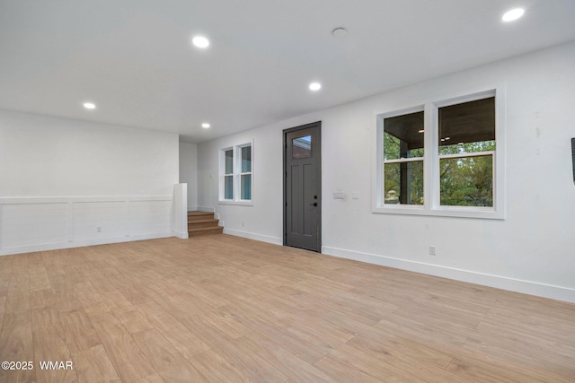 empty room featuring recessed lighting, baseboards, light wood finished floors, and stairway