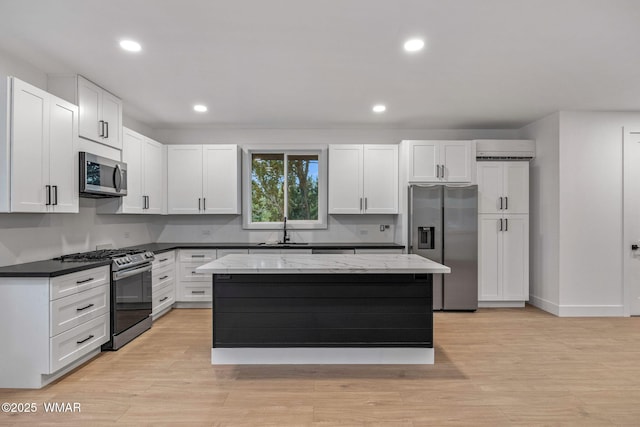 kitchen with a kitchen island, a sink, white cabinets, stainless steel appliances, and recessed lighting