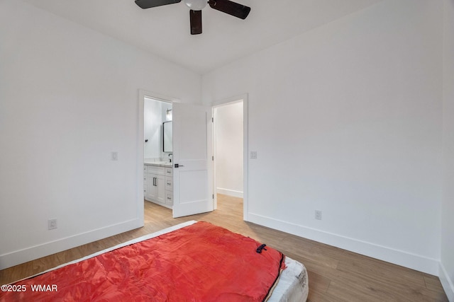 bedroom with baseboards, light wood finished floors, and ensuite bath
