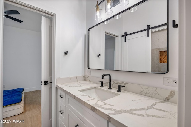 bathroom featuring vanity, a ceiling fan, baseboards, and wood finished floors