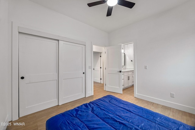 bedroom with ensuite bath, light wood-style floors, a ceiling fan, baseboards, and a closet