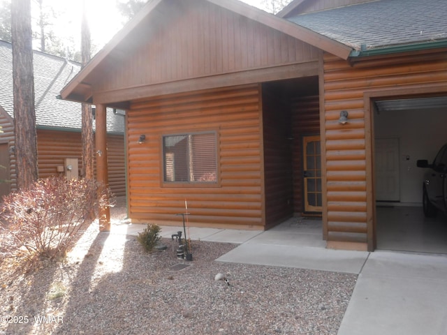 view of front of property with a shingled roof and log veneer siding