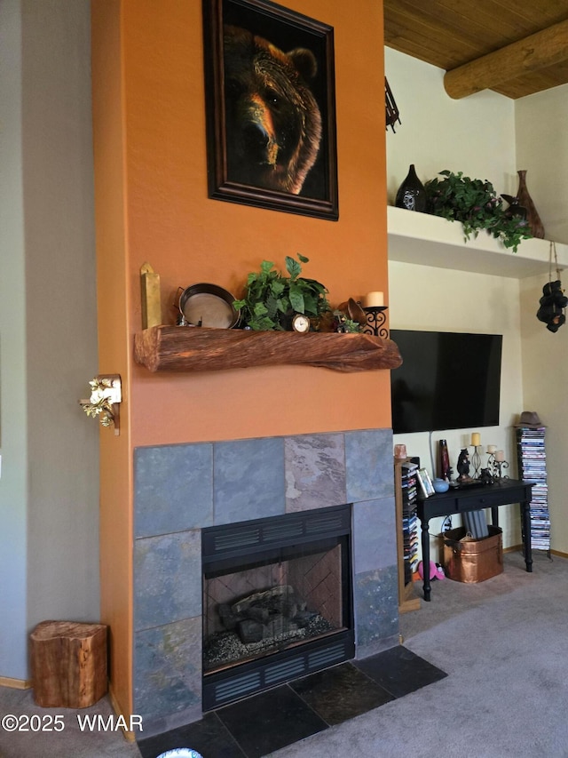 living area featuring beam ceiling, dark carpet, a tile fireplace, and wood ceiling