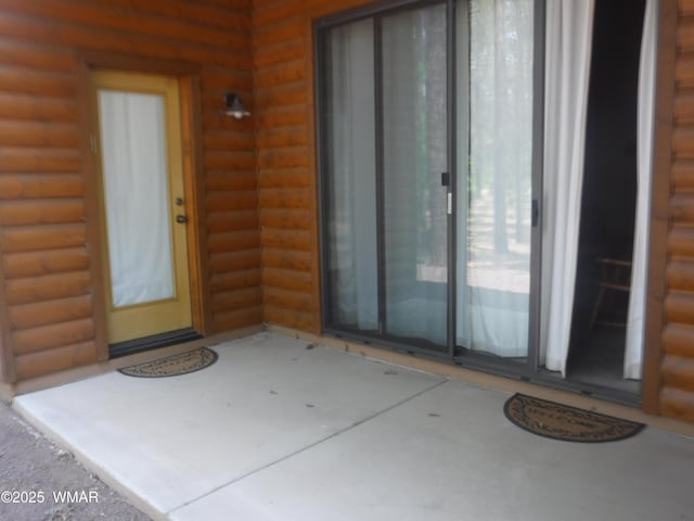 doorway to property featuring faux log siding