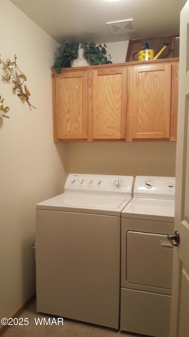 clothes washing area featuring visible vents, tile patterned flooring, washing machine and clothes dryer, and cabinet space