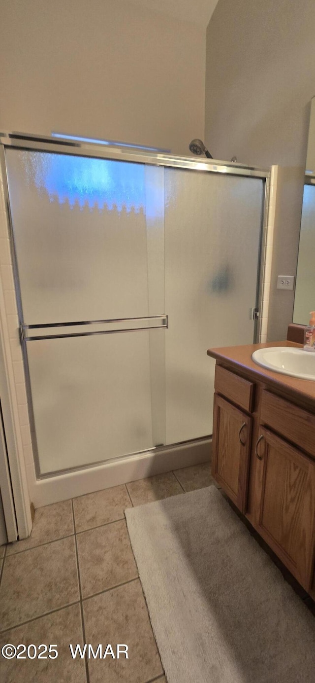 full bathroom featuring vanity, a shower with door, and tile patterned floors