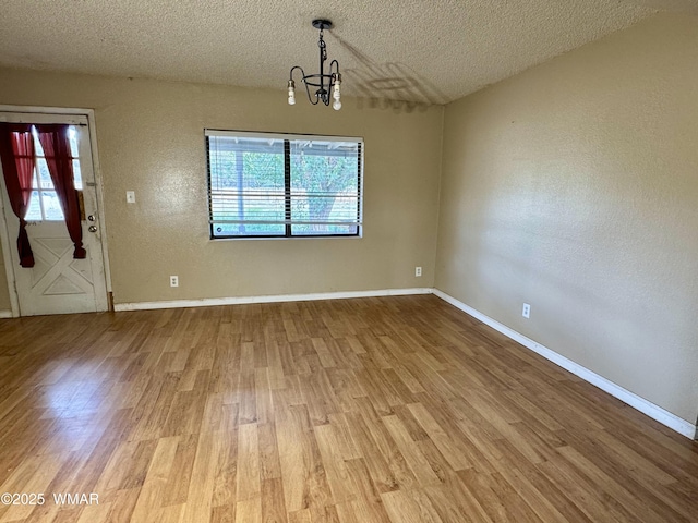 7124 Simons Way, Show Low, AZ 85901 - unfurnished dining area with a textured ceiling, light wood finished floors, a chandelier, plenty of natural light, and a textured wall