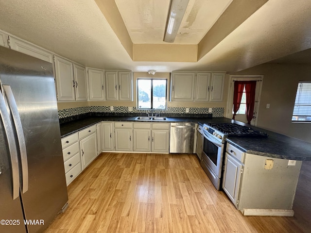 7124 Simons Way, Show Low, AZ 85901 - kitchen with appliances with stainless steel finishes, light wood-style flooring, dark countertops, a peninsula, and a raised ceiling