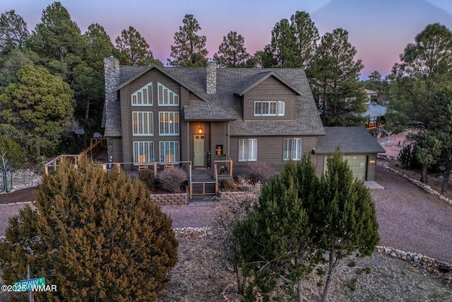 view of front of property featuring a garage, driveway, roof with shingles, and a chimney