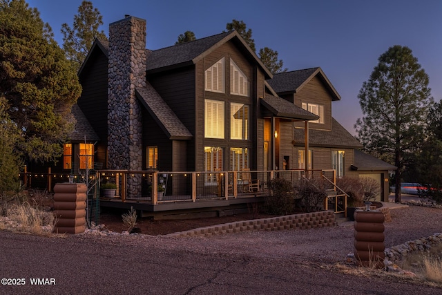 chalet / cabin with a garage, roof with shingles, and a chimney