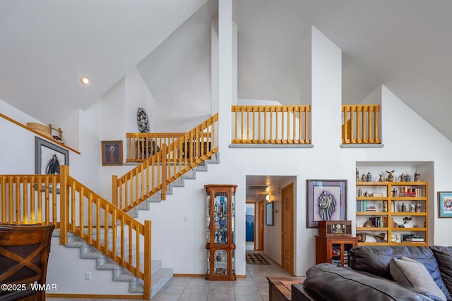 tiled living room featuring high vaulted ceiling and stairs