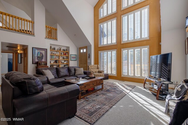 living room with a wealth of natural light, high vaulted ceiling, and carpet