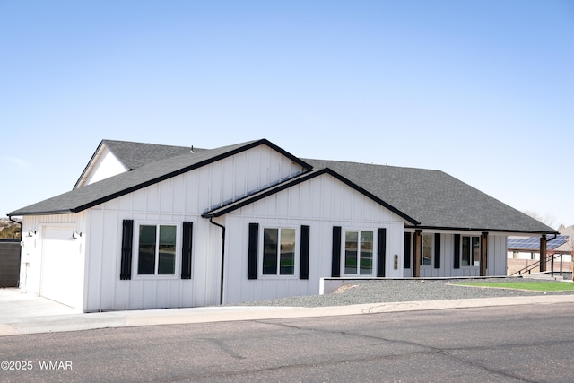 modern inspired farmhouse featuring an attached garage, board and batten siding, and roof with shingles