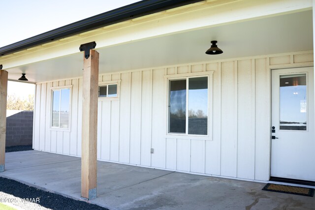 entrance to property with board and batten siding and a patio