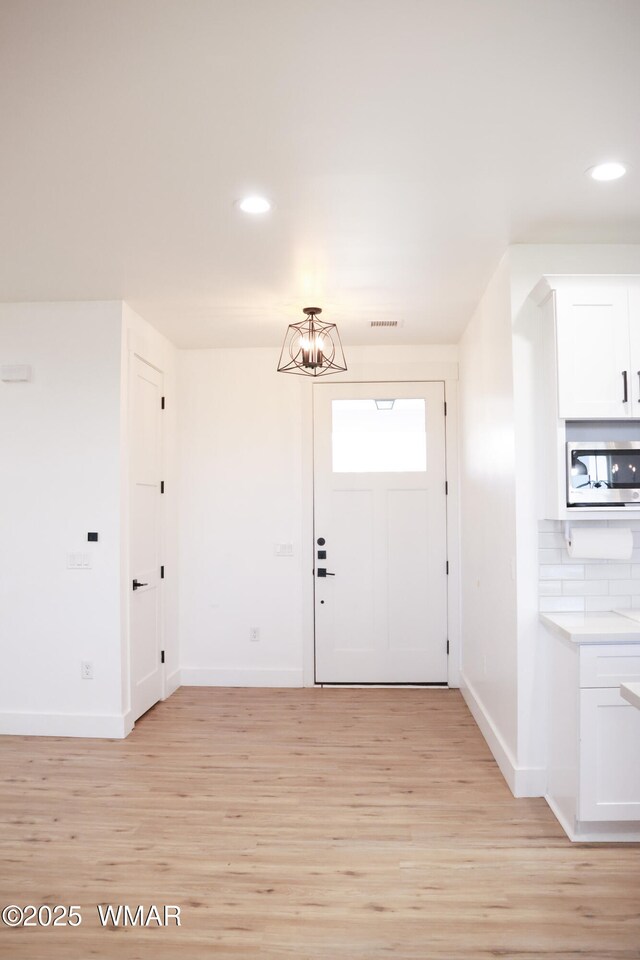 entryway featuring recessed lighting, visible vents, light wood-style flooring, a chandelier, and baseboards