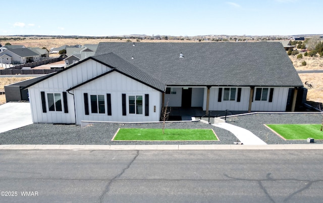 modern farmhouse with board and batten siding, a front yard, and a shingled roof