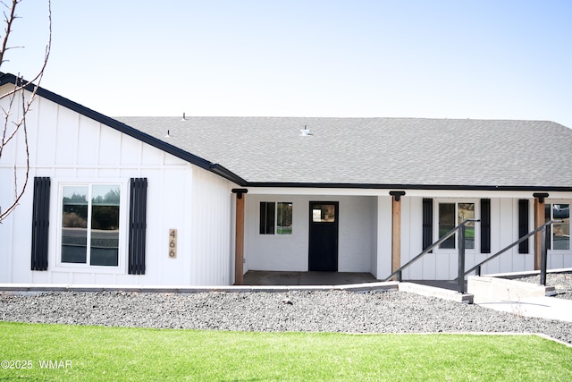 rear view of property featuring board and batten siding, roof with shingles, and a porch