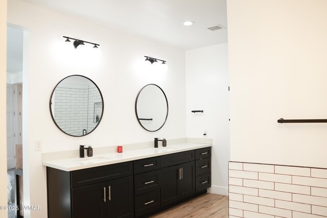 full bath featuring double vanity, visible vents, a sink, and wood finished floors