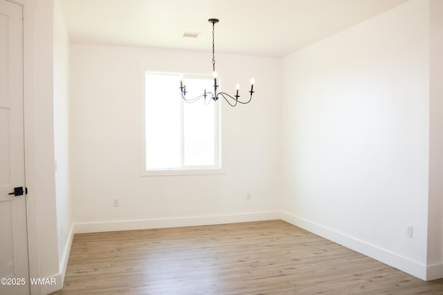 unfurnished dining area featuring baseboards, light wood finished floors, visible vents, and an inviting chandelier