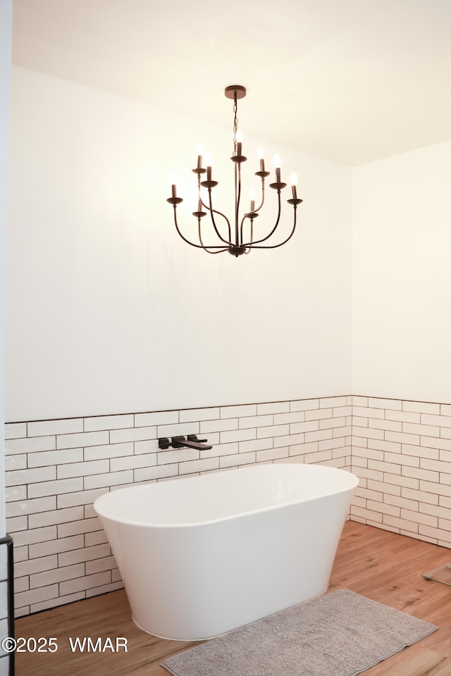 full bathroom with a soaking tub, tile walls, and wood finished floors