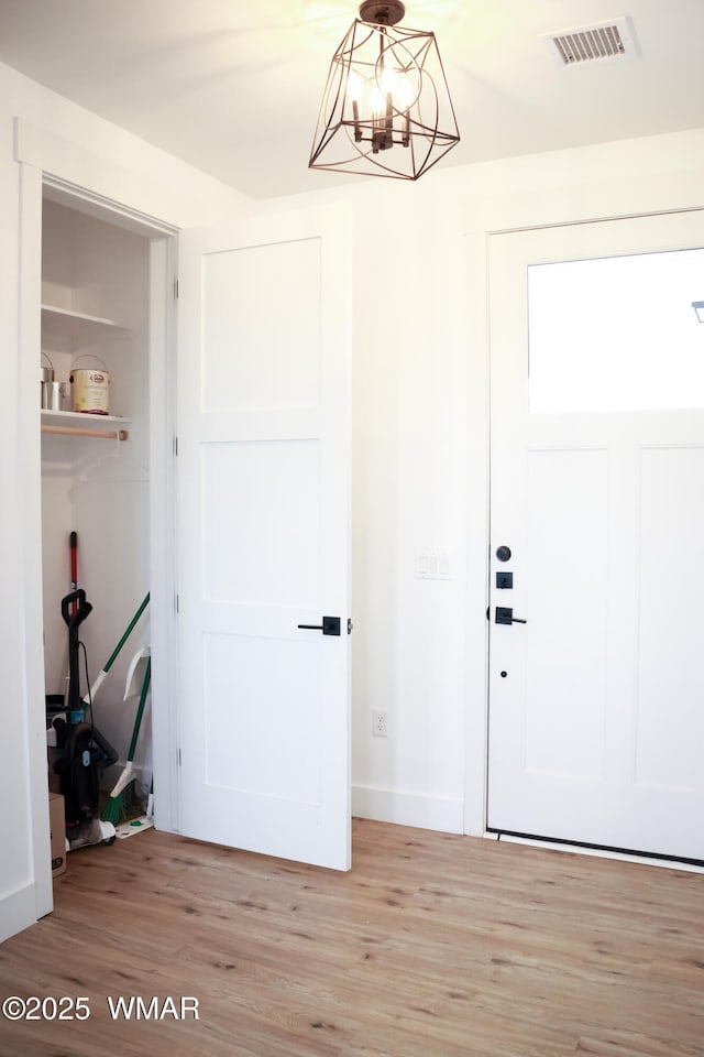 interior space with visible vents, a notable chandelier, light wood-style flooring, and baseboards