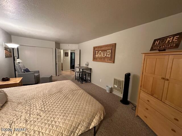 carpeted bedroom with a textured ceiling and a closet