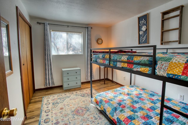 bedroom with a textured ceiling, baseboards, and wood finished floors