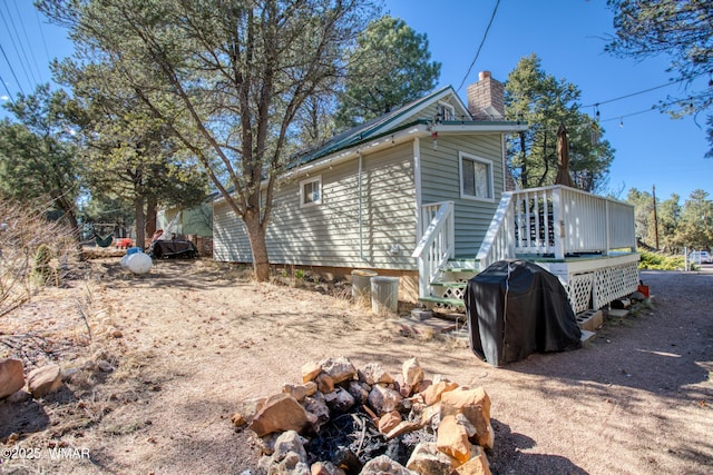 view of property exterior with a chimney and a deck