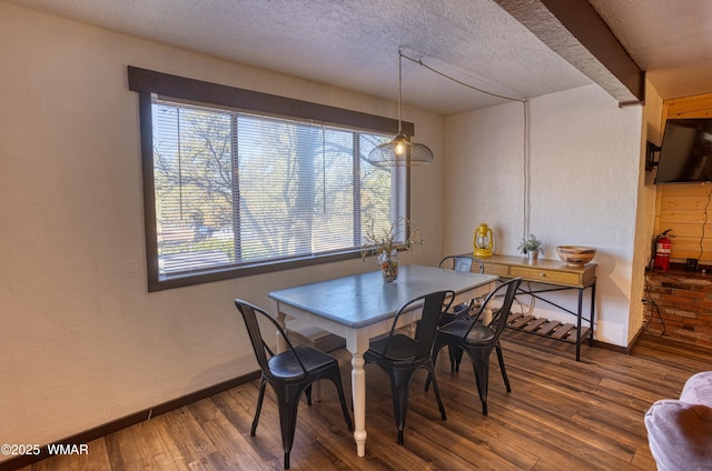 dining area featuring a textured wall, a textured ceiling, baseboards, and wood finished floors