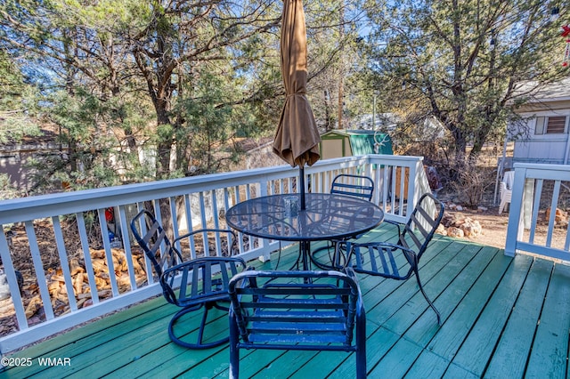 deck with outdoor dining space, a shed, and an outdoor structure