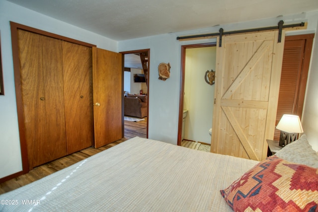 bedroom with a barn door, a closet, and wood finished floors