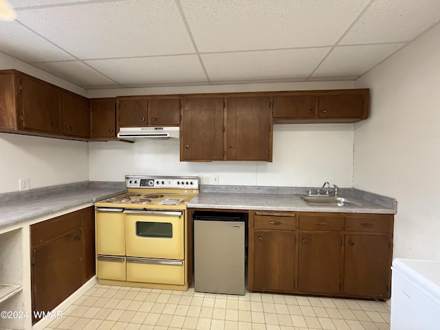 kitchen featuring stove, fridge, light countertops, under cabinet range hood, and a sink