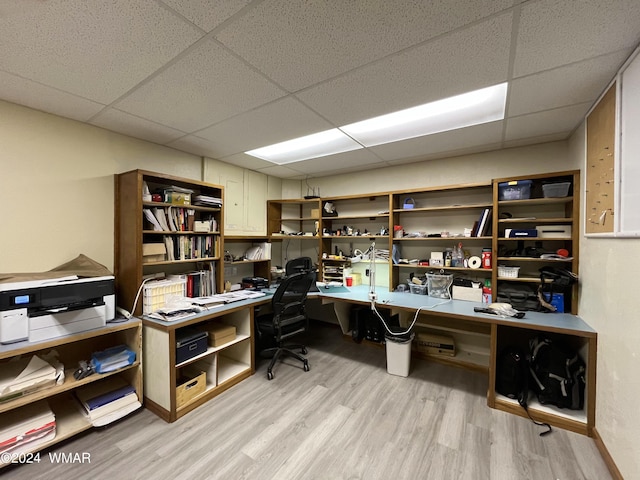 office space with a paneled ceiling, light wood-style flooring, and built in desk