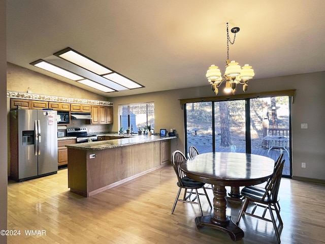 kitchen with stainless steel appliances, a peninsula, hanging light fixtures, brown cabinets, and lofted ceiling with skylight