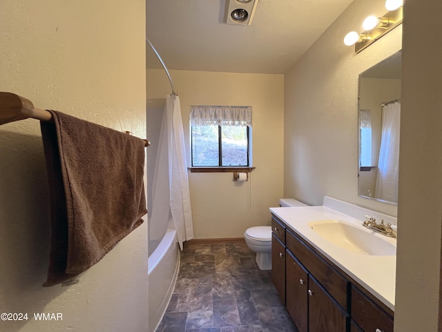 bathroom featuring toilet, shower / tub combo, stone finish floor, vanity, and baseboards